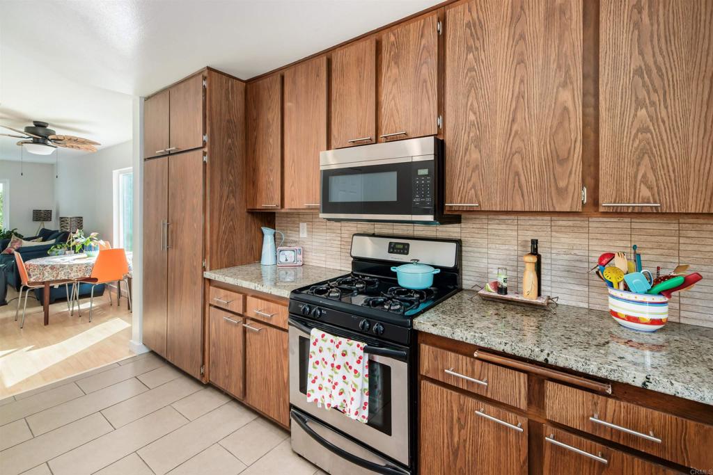 4239 Vista Del Rio Way, Unit 6 Oceanside, CA 92057 - Photo 9 of 30 a kitchen with stainless steel appliances granite countertop a stove a sink and a microwave