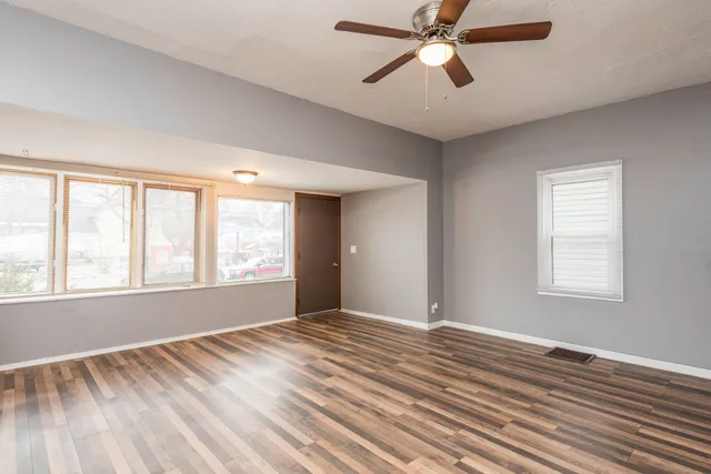 a view of an empty room with a window and wooden floor