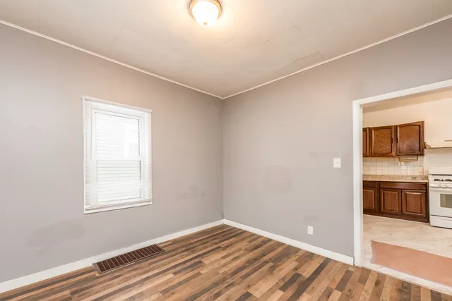 a view of an empty room with a window and wooden floor