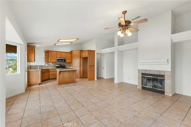 a kitchen with stainless steel appliances kitchen island granite countertop a refrigerator a stove a sink dishwasher and a fireplace with wooden floor