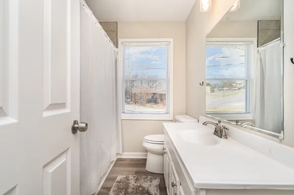 a bathroom with a sink a toilet a mirror and a window