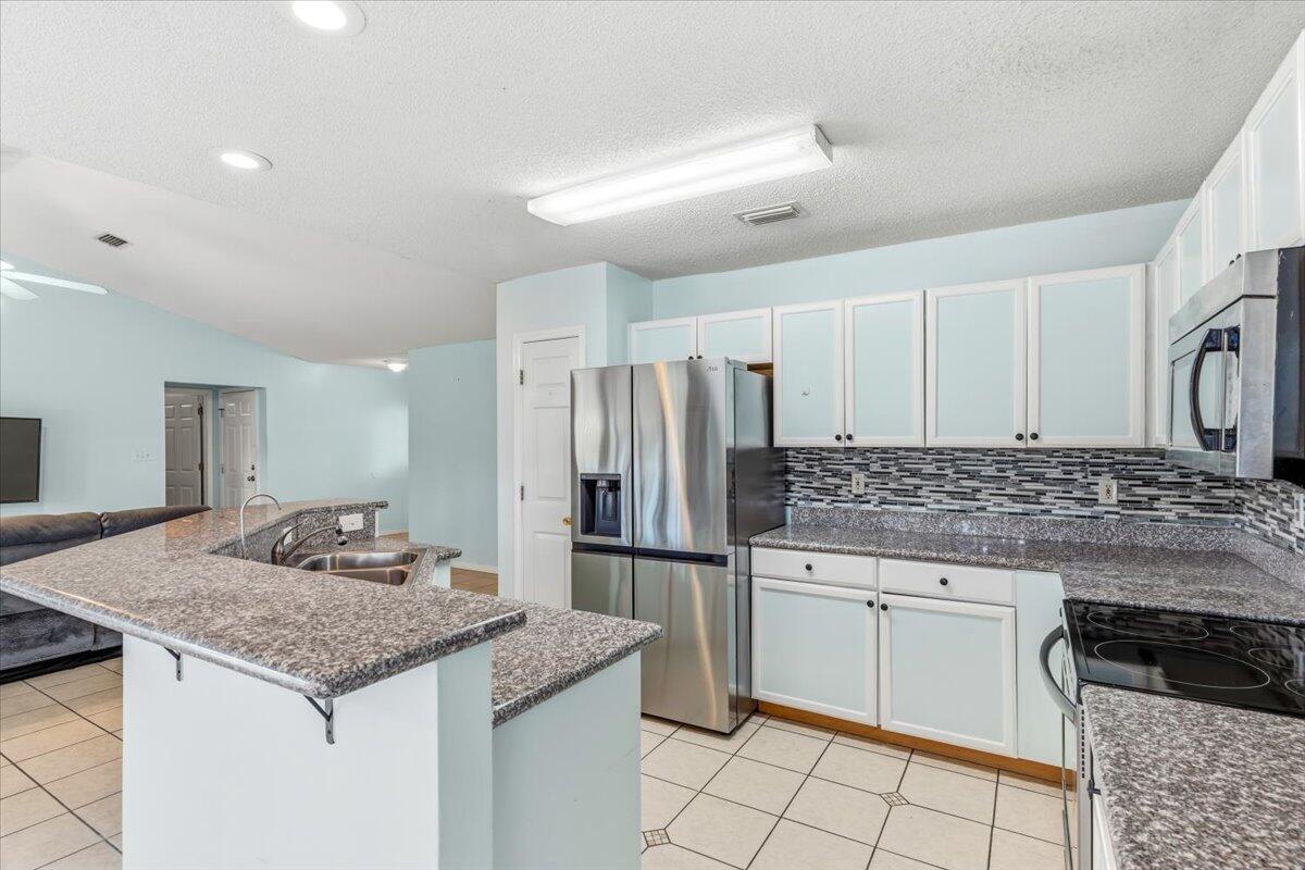7095 Jasper Street Navarre, FL 32566 - Photo 12 of 26 a kitchen with granite countertop a sink stove and refrigerator