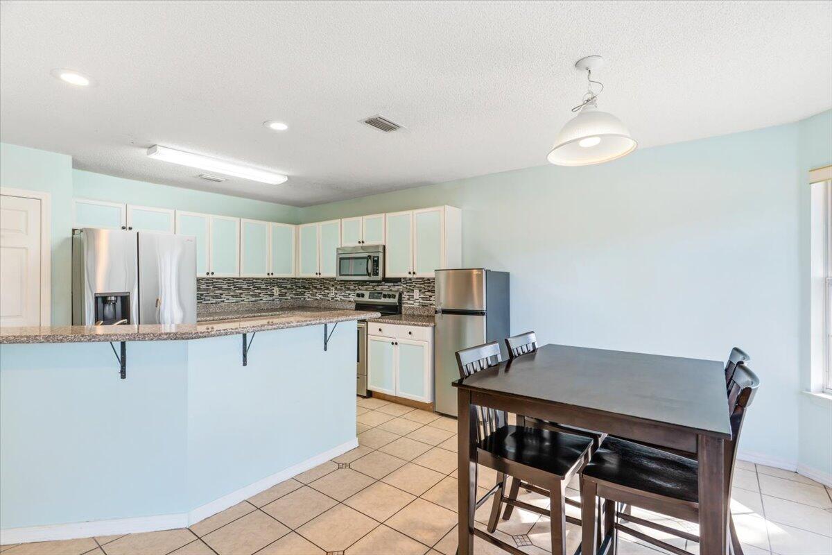 7095 Jasper Street Navarre, FL 32566 - Photo 13 of 26 a kitchen with a table chairs microwave and cabinets