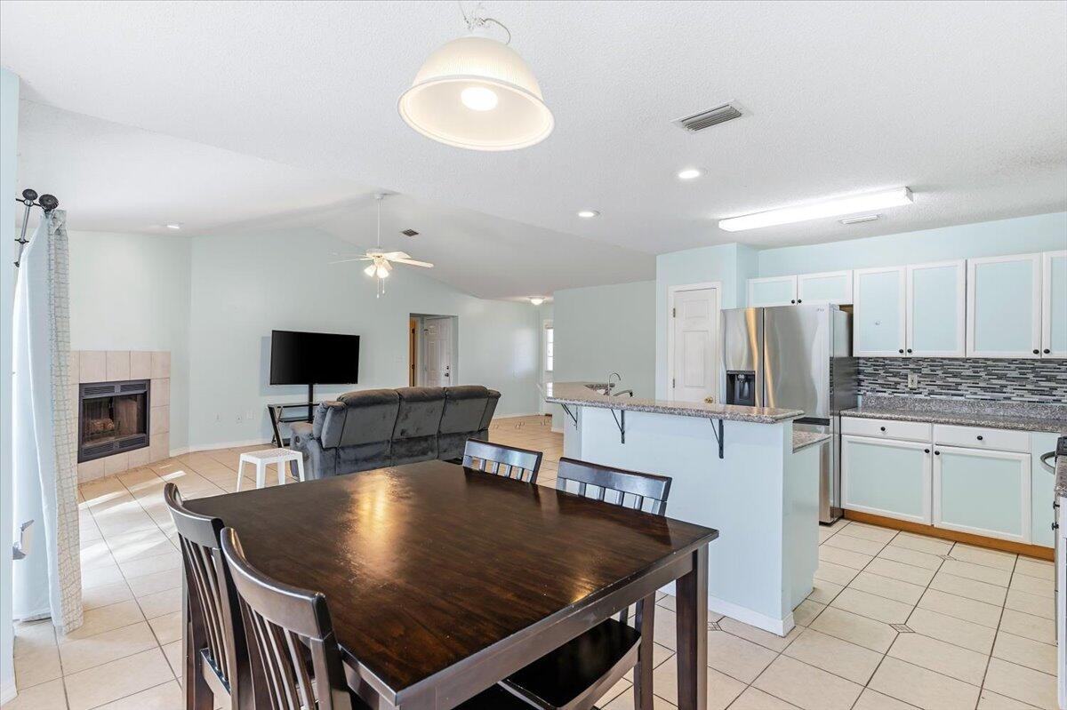 7095 Jasper Street Navarre, FL 32566 - Photo 14 of 26 a kitchen with stainless steel appliances granite countertop a stove top oven a sink dishwasher a dining table and chairs