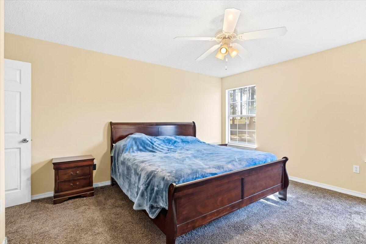 7095 Jasper Street Navarre, FL 32566 - Photo 17 of 26 a bed sitting in a room next to a window and a chandelier