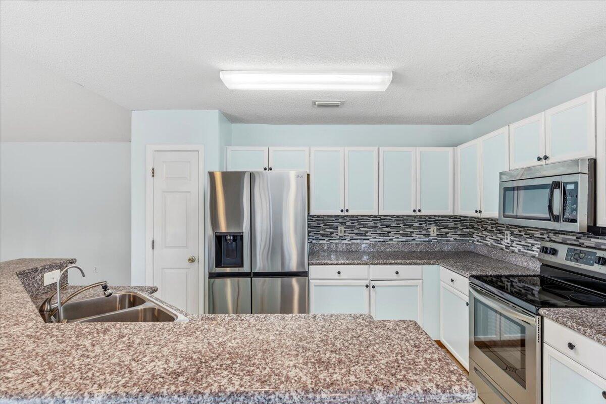 7095 Jasper Street Navarre, FL 32566 - Photo 2 of 26 a kitchen with granite countertop a refrigerator stove and sink