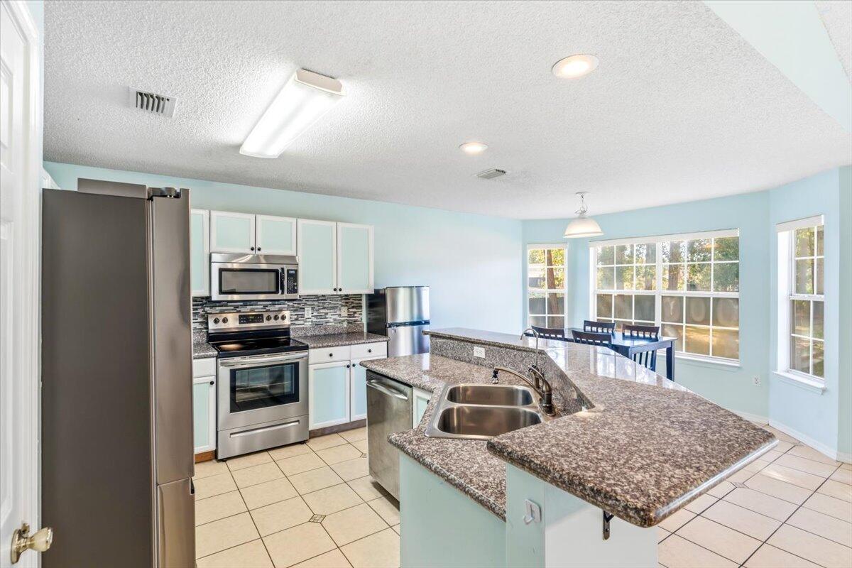7095 Jasper Street Navarre, FL 32566 - Photo 3 of 26 a kitchen with stainless steel appliances granite countertop a sink stove and refrigerator