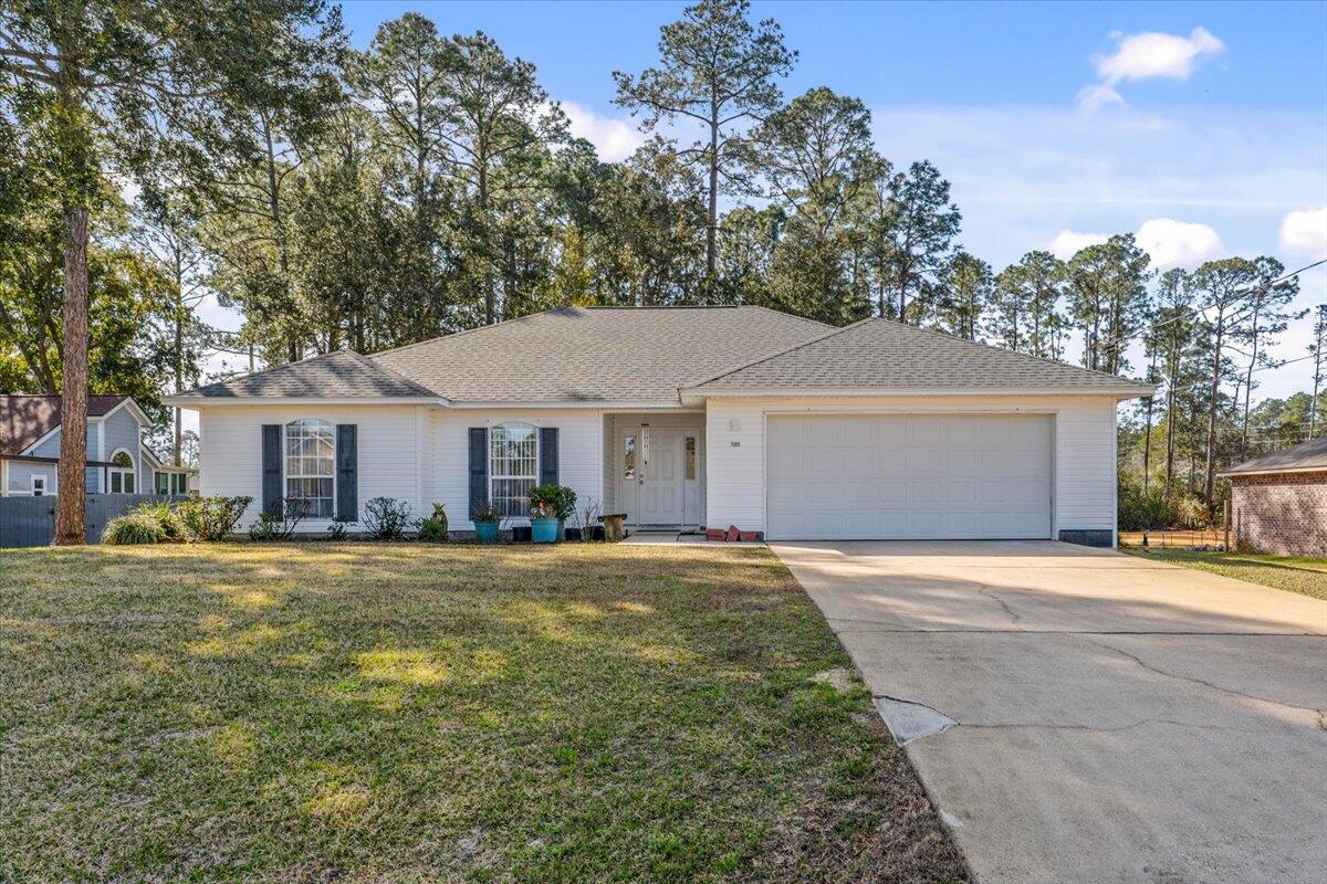 7095 Jasper Street Navarre, FL 32566 - Photo 8 of 26 a front view of a house with a garden and trees