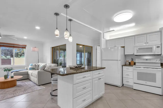 a kitchen with granite countertop white cabinets and white appliances
