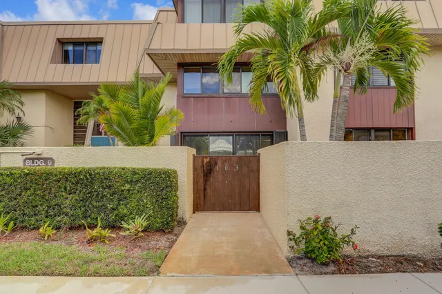 a view of a white house with a big yard and potted plants