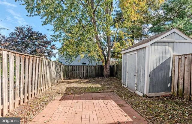 a view of backyard with small cabin and wooden fence