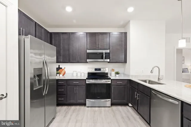a kitchen with stainless steel appliances a sink a stove a refrigerator and cabinets