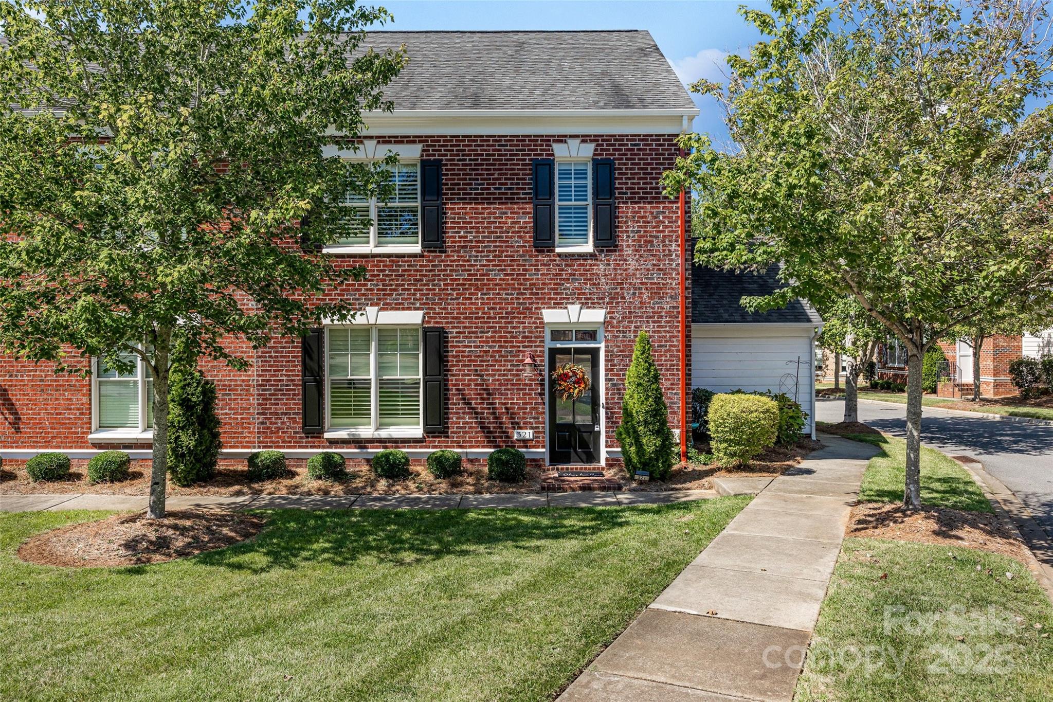 a front view of a house with a yard and tree