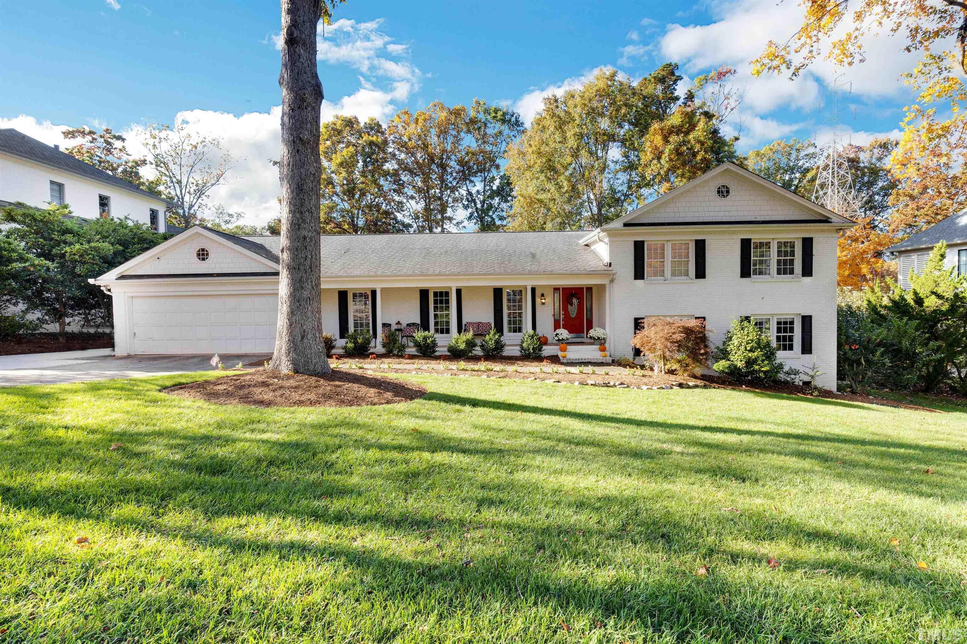 a view of a white house with a big yard and potted plants