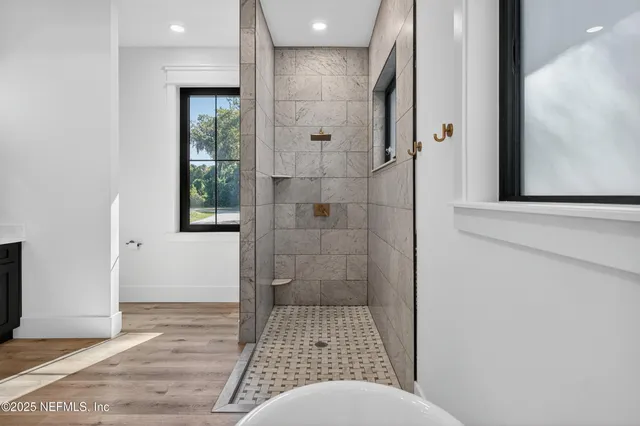 a bedroom with a bed a mirror on dresser and a large window