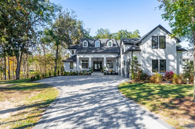 a view of a white house with a big yard and large trees