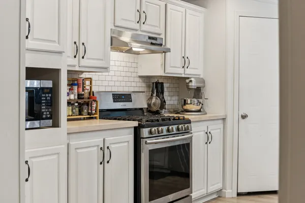 a kitchen with stainless steel appliances granite countertop white cabinets and a stove