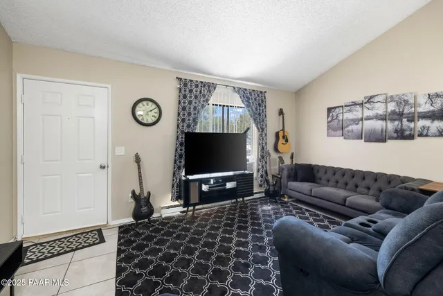 a living room with furniture a flat screen tv and kitchen view