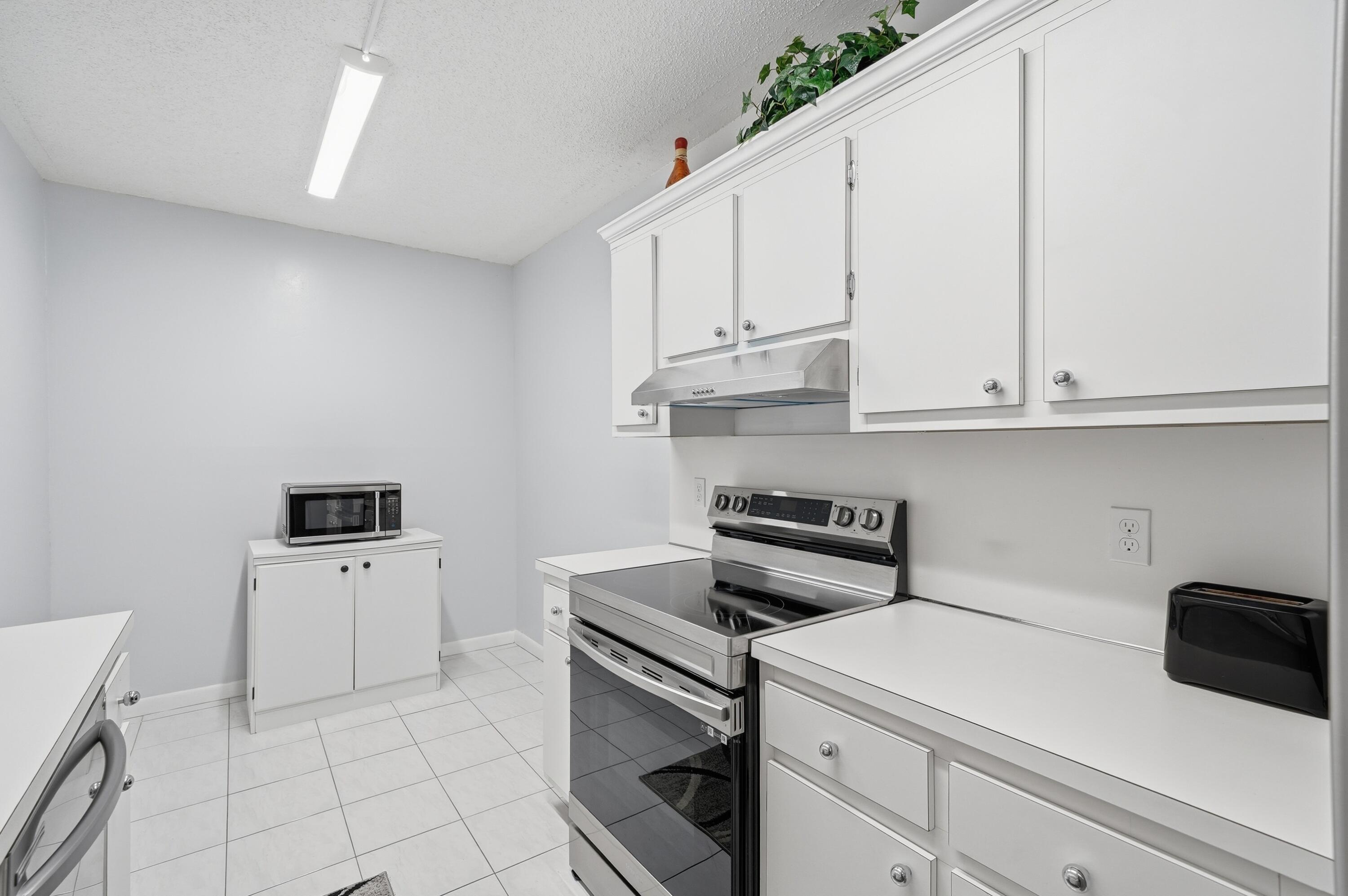 3850 Washington Street, Unit 1003 Hollywood, FL 33021 - Photo 9 of 30 a kitchen with white cabinets and white appliances