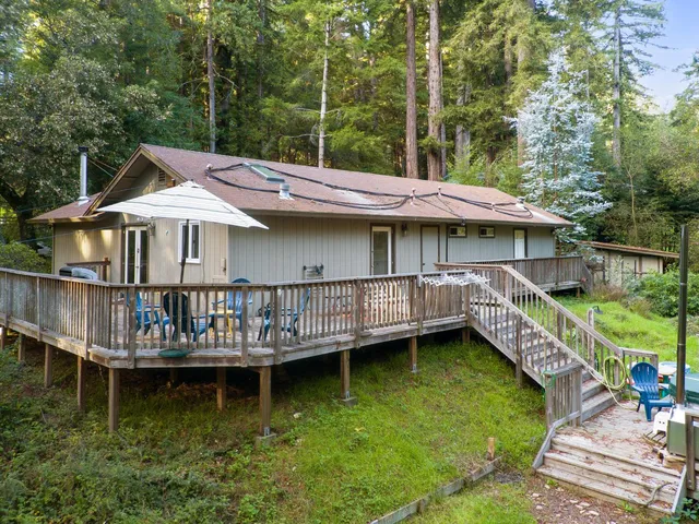 a front view of a house with a wooden deck and a yard