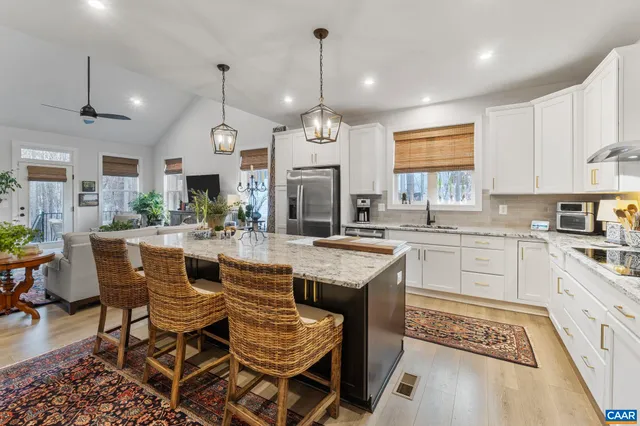 a open kitchen with stainless steel appliances granite countertop a stove a sink a refrigerator a dining table and chairs with wooden floor