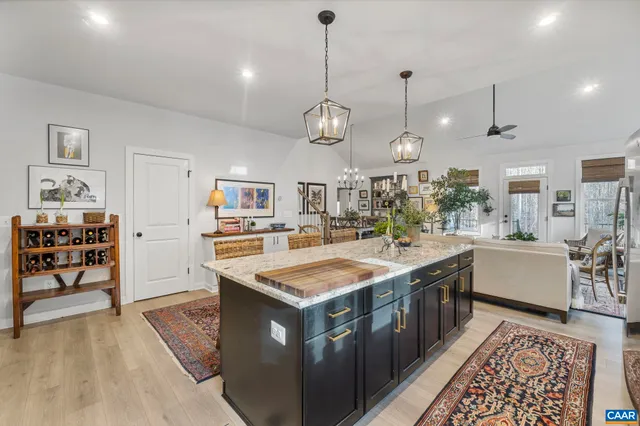 a large kitchen with stainless steel appliances granite countertop a sink dishwasher a stove and a dining table with wooden floor