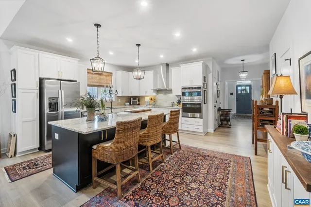 a kitchen with stainless steel appliances kitchen island granite countertop a table chairs and a refrigerator