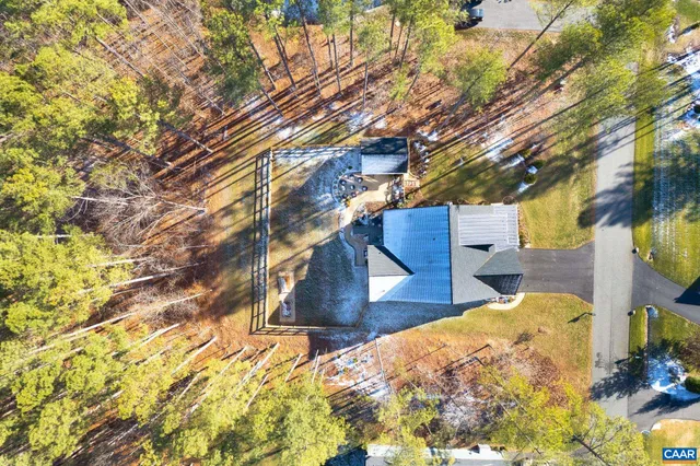 a view of a white house next to a yard with plants and trees