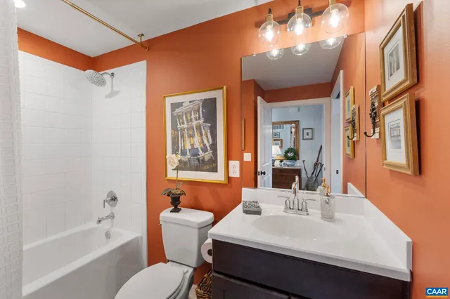 a bathroom with a sink a toilet a mirror a vanity and bathtub