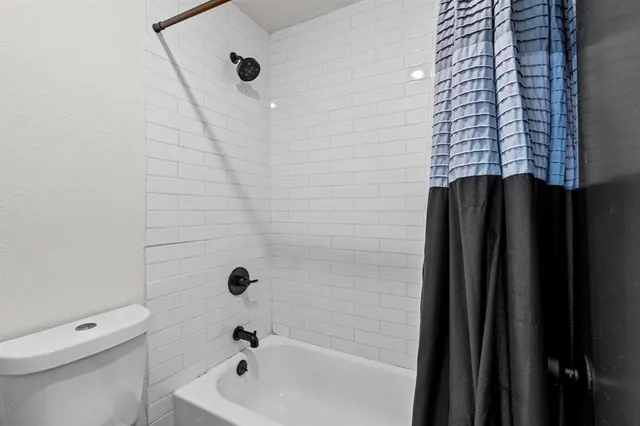 a bathroom with a shower a toilet and a tub