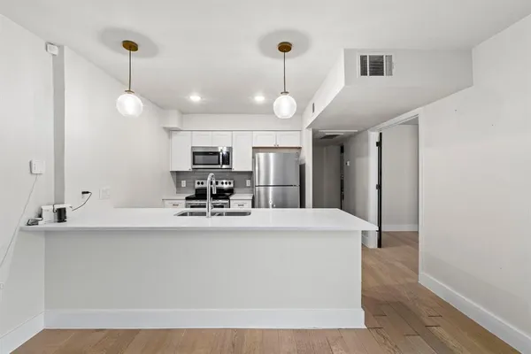 a large white kitchen with a large counter top appliances and cabinets
