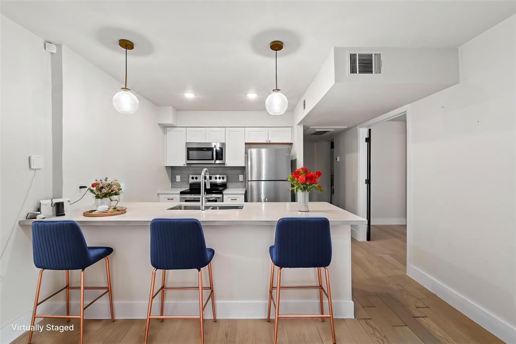 909 Reinli Street, Unit 101 Austin, TX 78751 - Photo 4 of 34 a kitchen with stainless steel appliances kitchen island granite countertop a dining table chairs and a refrigerator