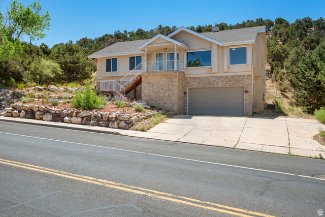 790 East Fiddlers Canyon Road Cedar City, UT 84721 - Photo 2 of 35 Two-story residence featuring a multi-tone exterior finish, a two-car garage with a panel door, and a front balcony with a white railing