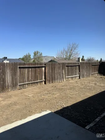a view of a house with backyard and wooden fence