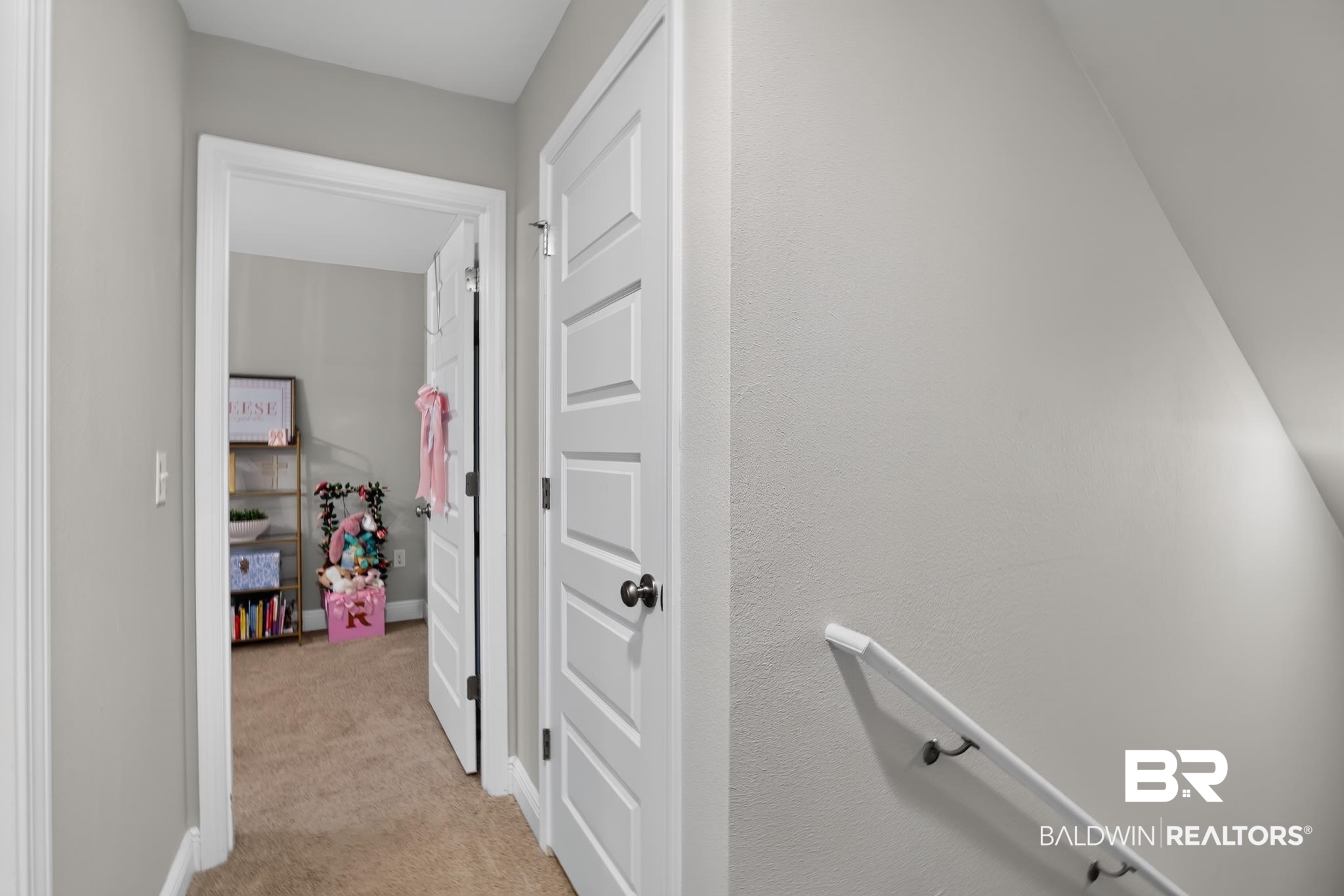 1210 Primrose Lane Foley, AL 36535 - Photo 20 of 33 Interior hallway featuring neutral wall tones, white five-panel doors, and a staircase with a white handrail