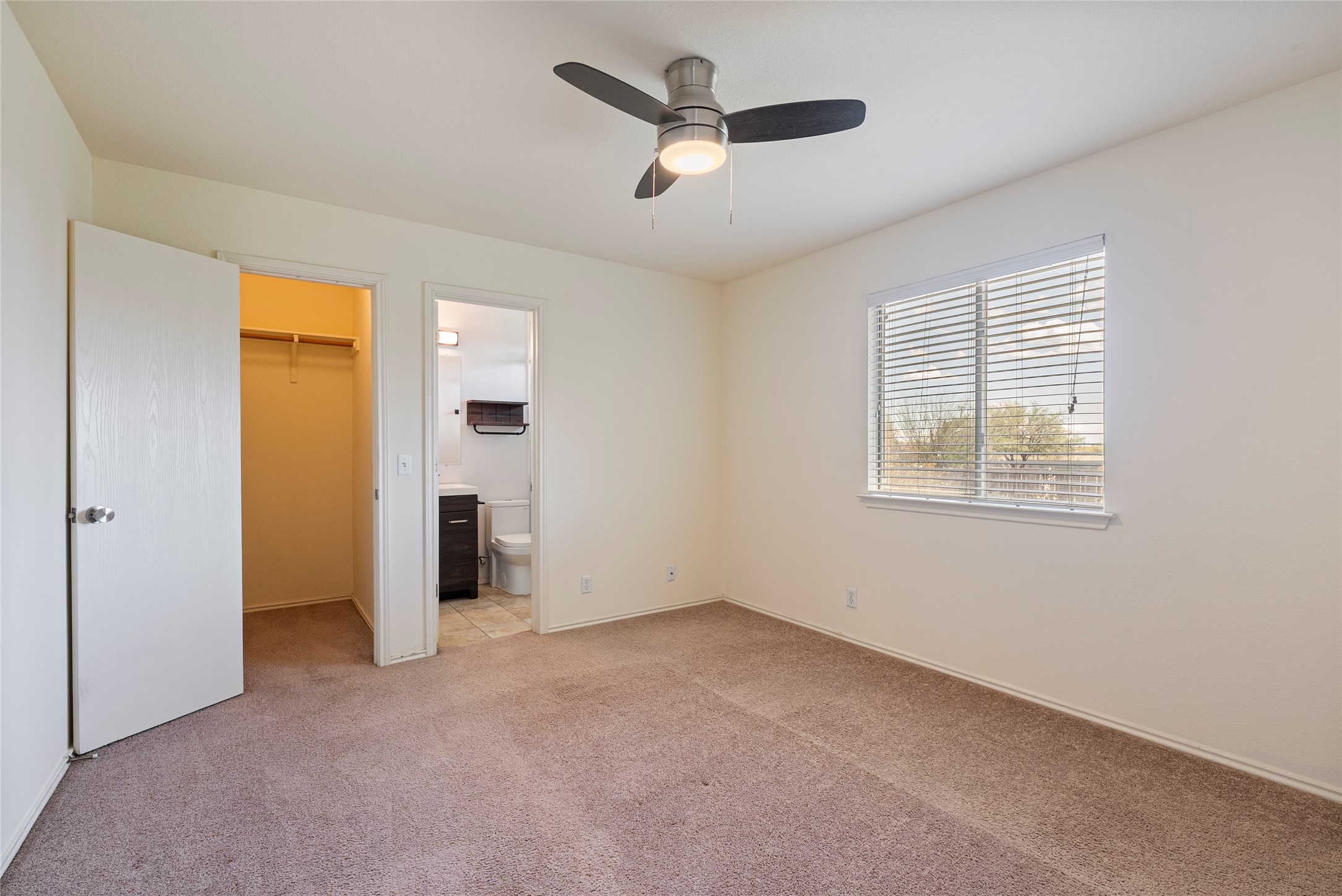 348 Atlantis Kyle, TX 78640 - Photo 12 of 17 Unfurnished bedroom featuring a spacious closet, light colored carpet, a ceiling fan, and connected bathroom