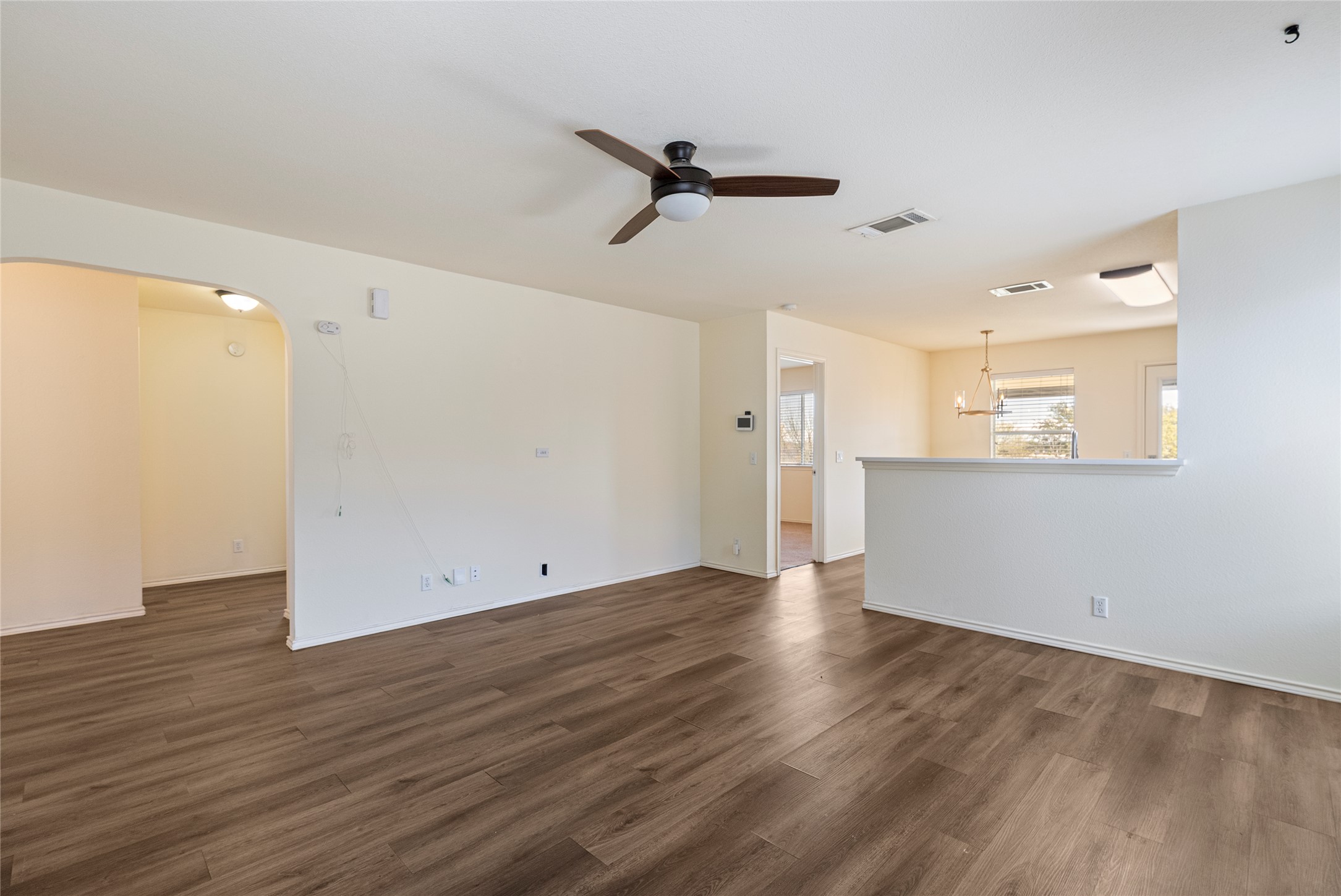 348 Atlantis Kyle, TX 78640 - Photo 4 of 17 Unfurnished living room featuring ceiling fan, dark wood-style flooring, and arched walkways