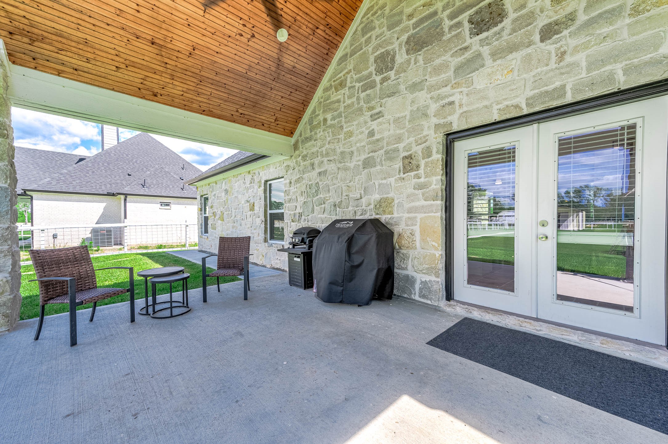 8032 Short Road Needville, TX 77461 - Photo 29 of 50 Another angle of the covered patio showcases the inviting outdoor seating area, stone exterior accents, and spacious setup ideal for entertaining or relaxing while enjoying views of the backyard.