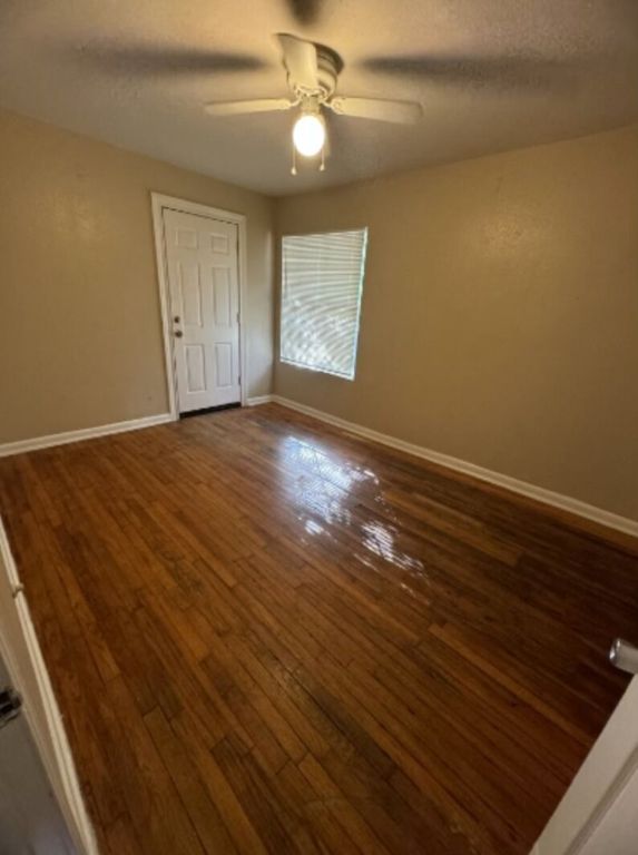 203 North Street, Unit A Kyle, TX 78640 - Photo 5 of 8 an empty room with wooden floor chandelier fan and windows