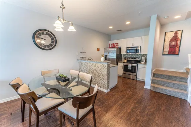 a view of a dining room with furniture a chandelier and kitchen view