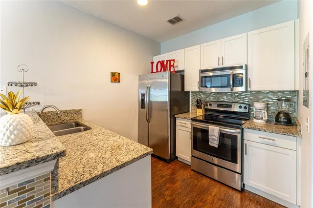 a kitchen with granite countertop a stove top oven and refrigerator