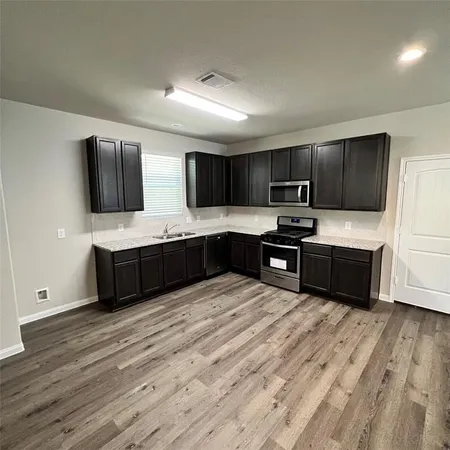 a large kitchen with stainless steel appliances granite countertop a stove a sink and a microwave