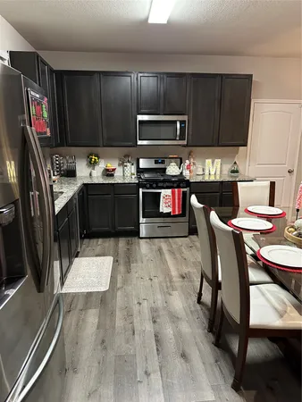 a kitchen with granite countertop a stove top oven a sink dishwasher a dining table and chairs with wooden floor