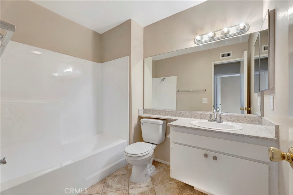 2670 West Segerstrom Avenue, Unit F Santa Ana, CA 92704 - Photo 23 of 28 a bathroom with a granite countertop sink a toilet and a mirror