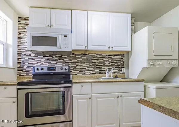 a kitchen with granite countertop white cabinets and stainless steel appliances