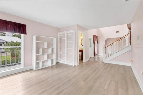 a view of an empty room with wooden floor and windows