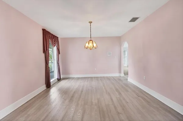 a view of an empty room with wooden floor and windows