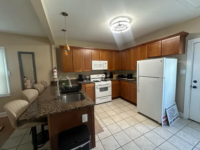 a kitchen with granite countertop a refrigerator a stove a sink dishwasher and a refrigerator with wooden floor