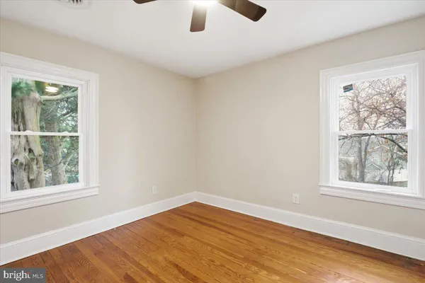 a view of an empty room with a window and wooden floor