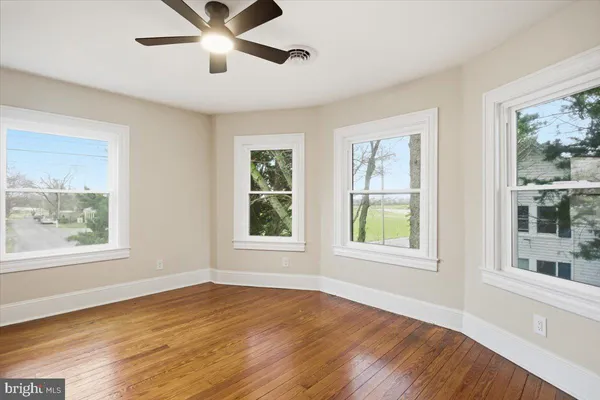 a view of an empty room with a window and wooden floor